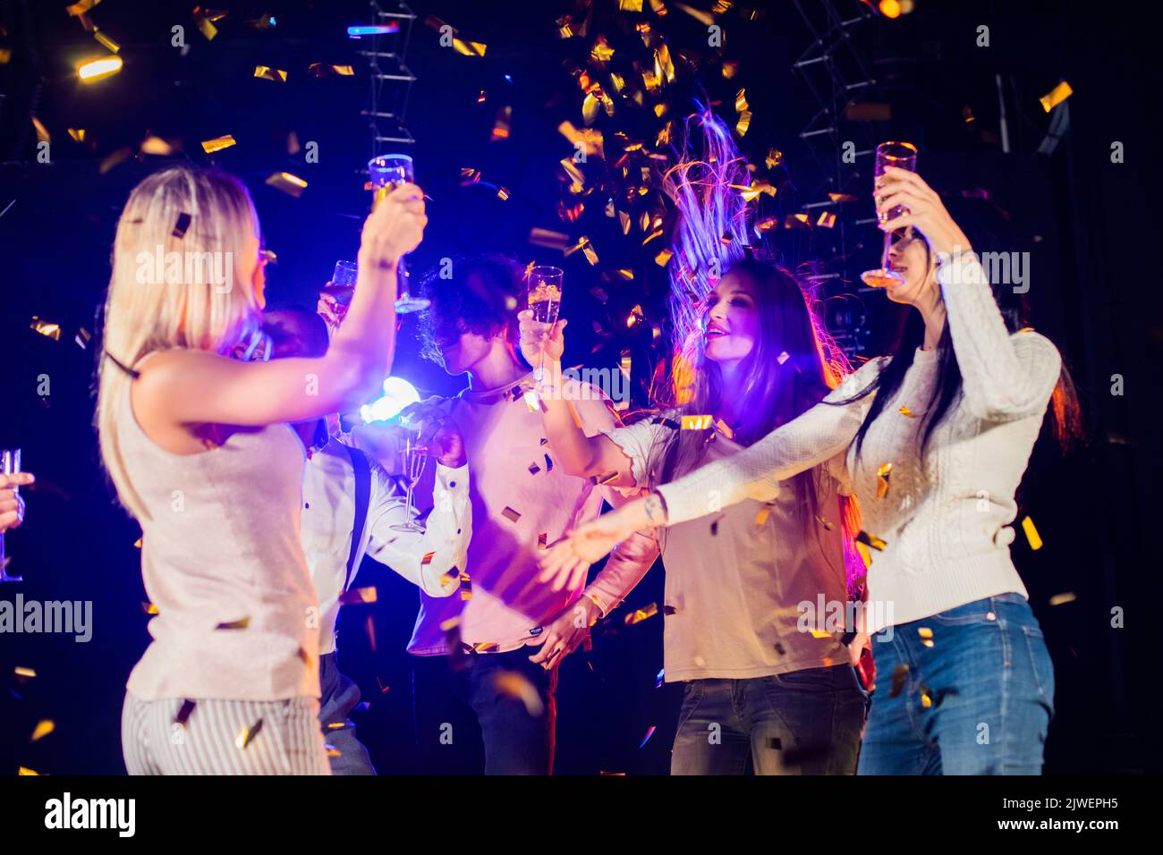 Group of friends dancing in nightclub celebrating with champagne Stock Photo