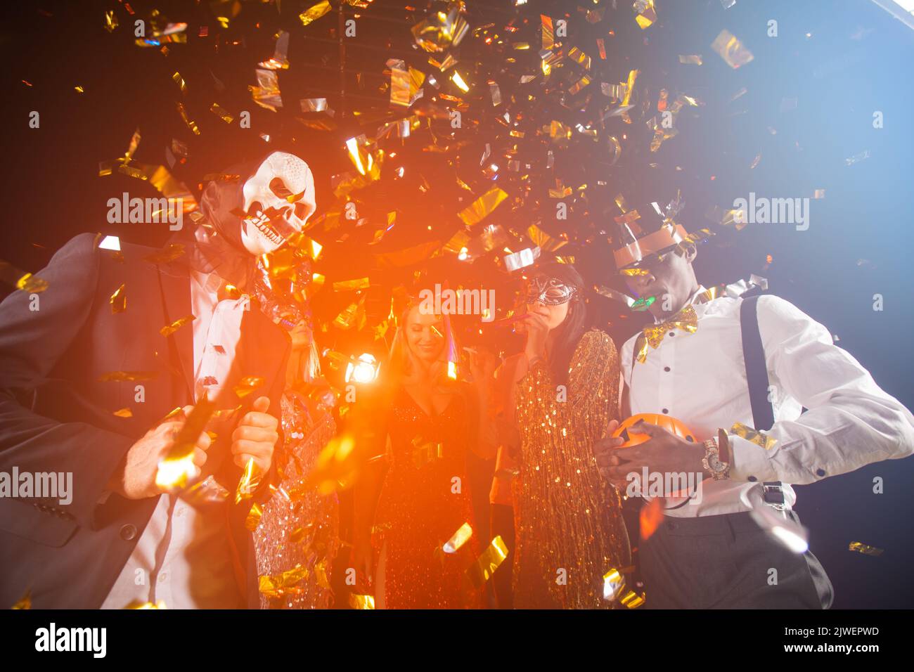 People dance at Halloween party with champagne glasses. Friends in the costumes in nightclub Stock Photo
