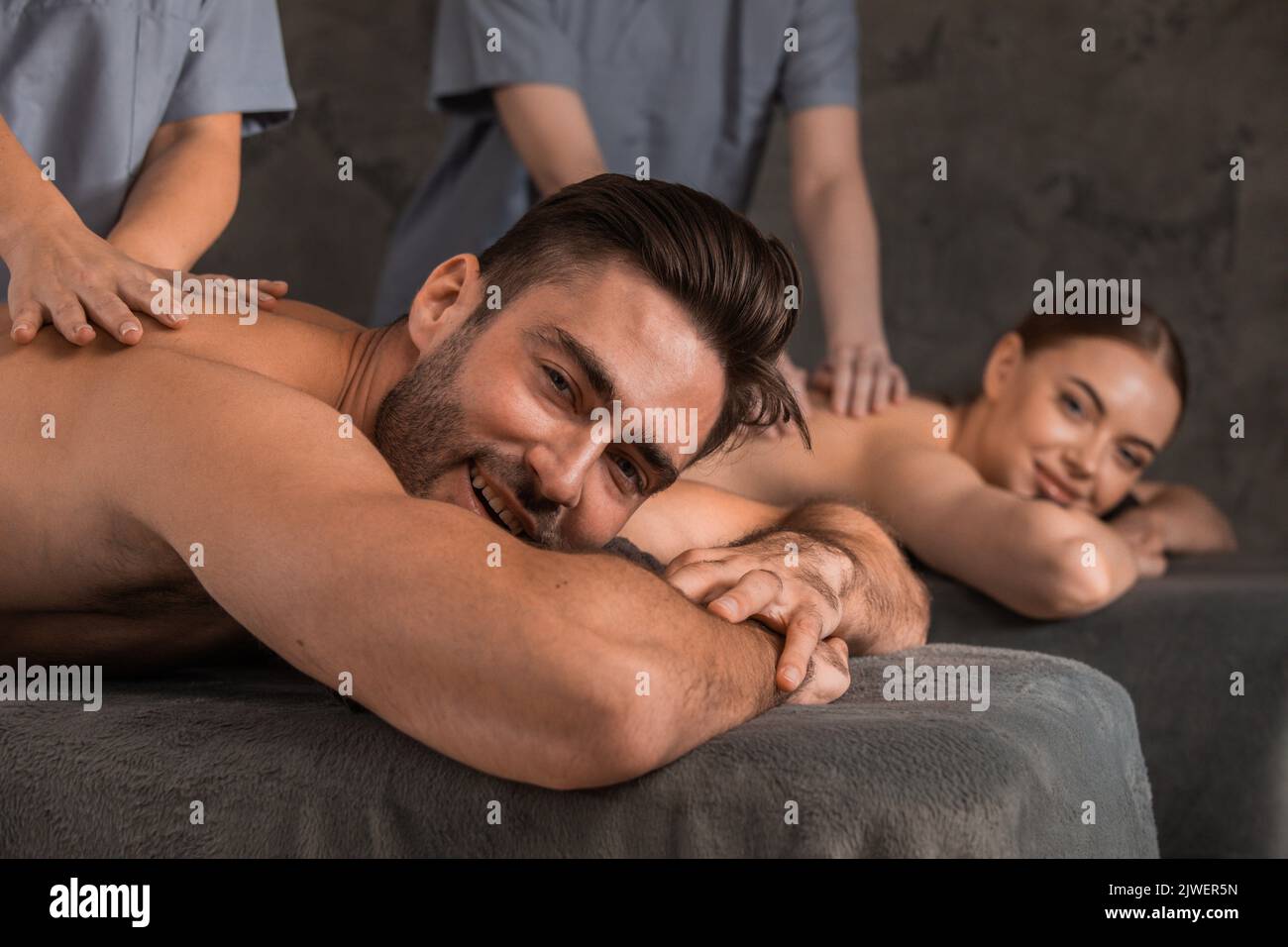 Happy young couple enjoying spa procedures, back massage Stock Photo