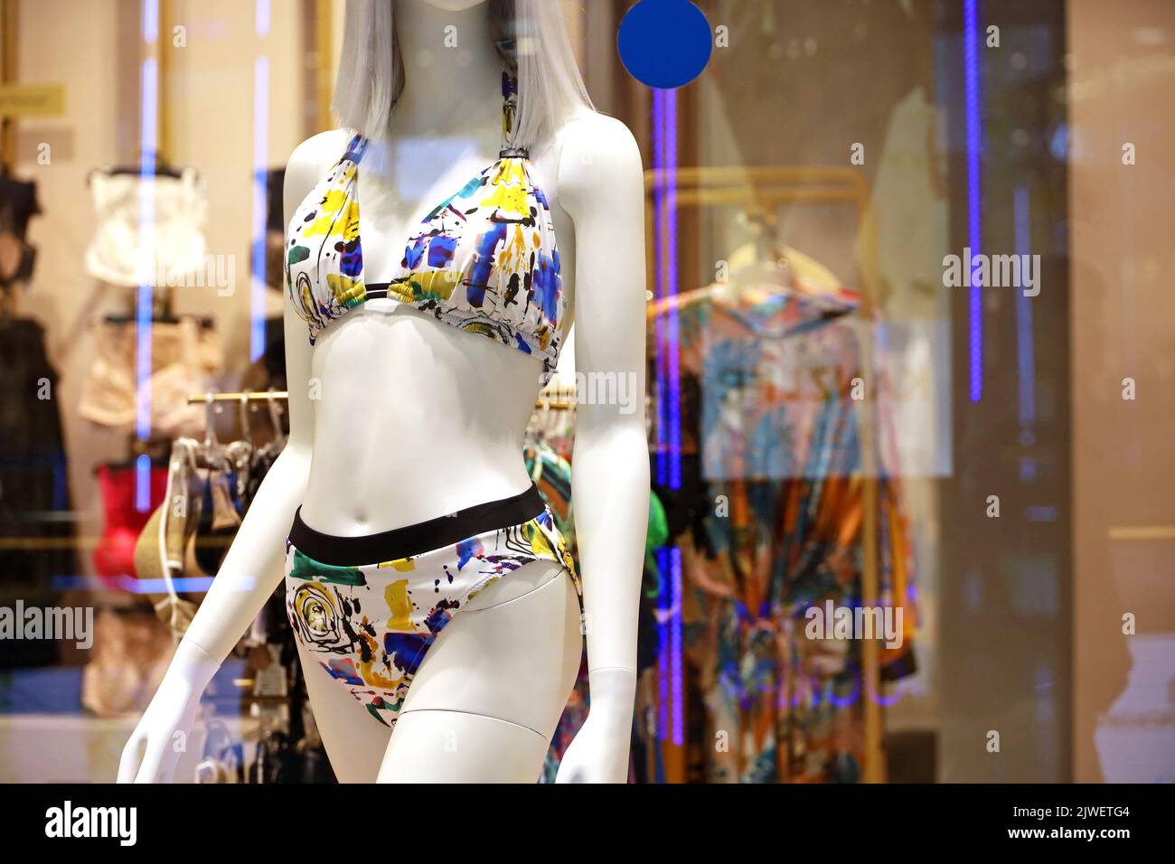 Female mannequin in colorful swimsuit. Lingerie store, swimwear for beach holidays, view through the glass Stock Photo