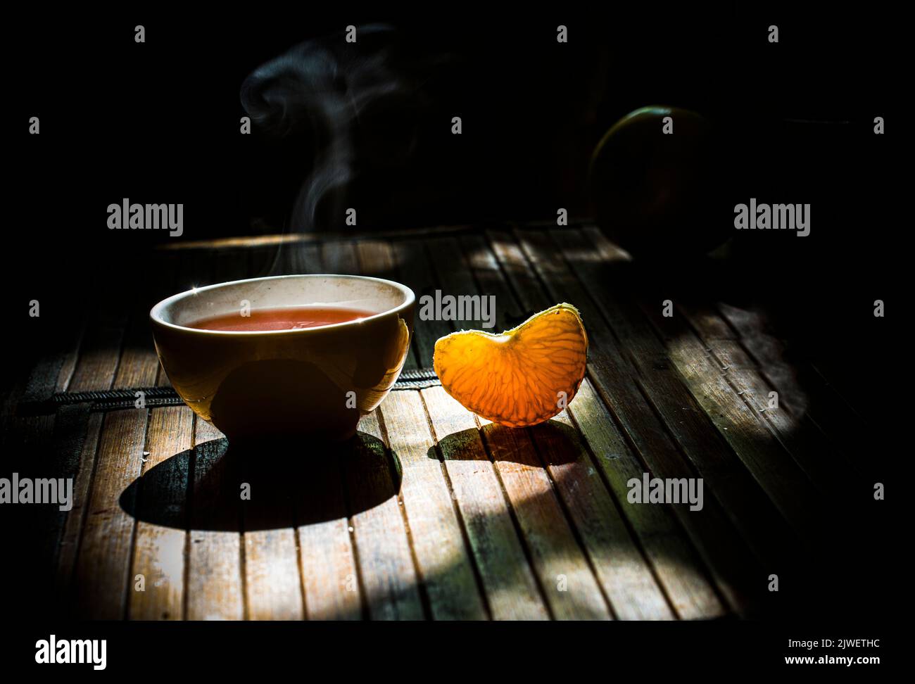 A cup of hot pu-ehr tea, and a slice of tangerine Stock Photo