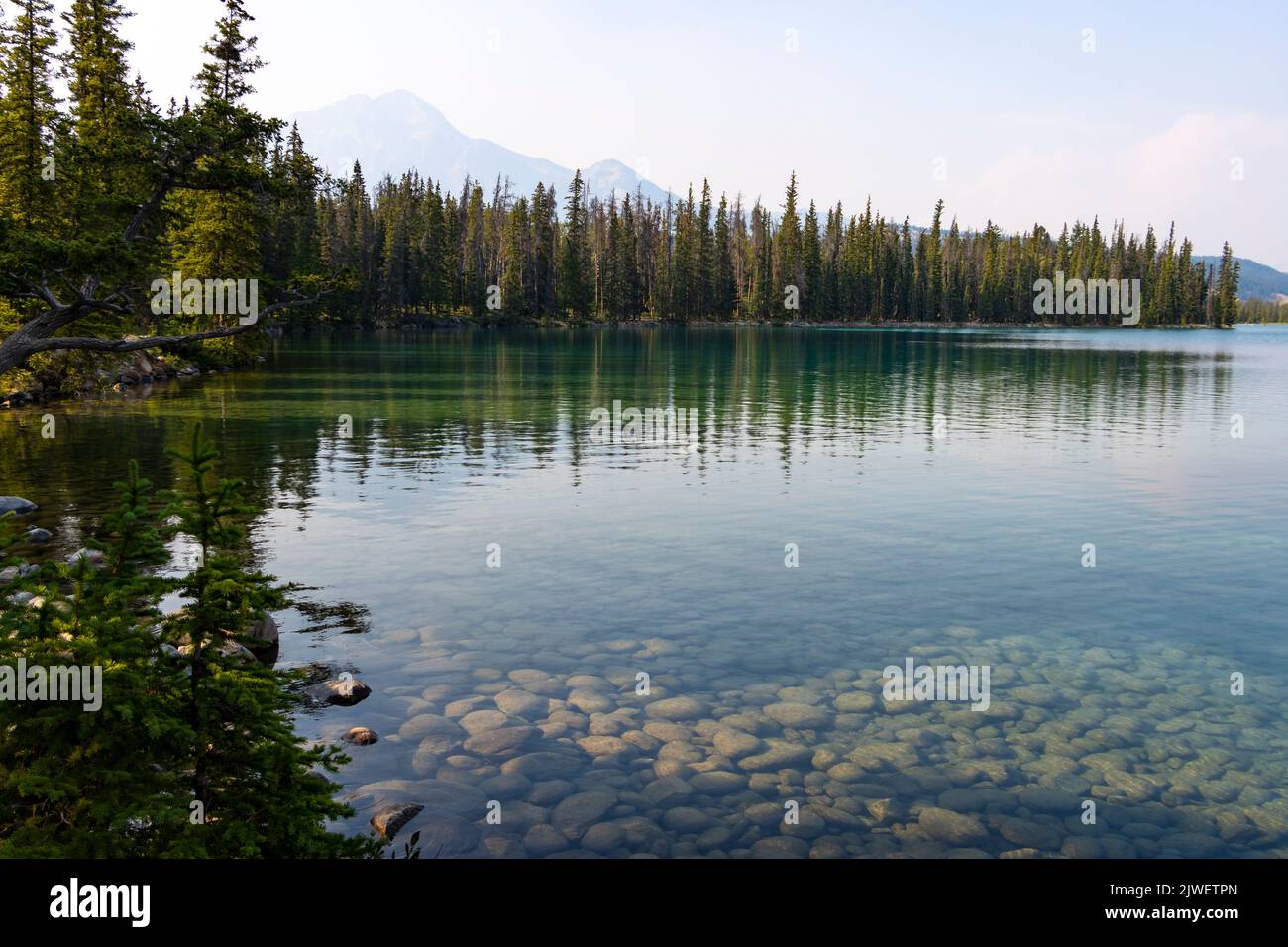 clear calm lake with mountains far off in distance Stock Photo
