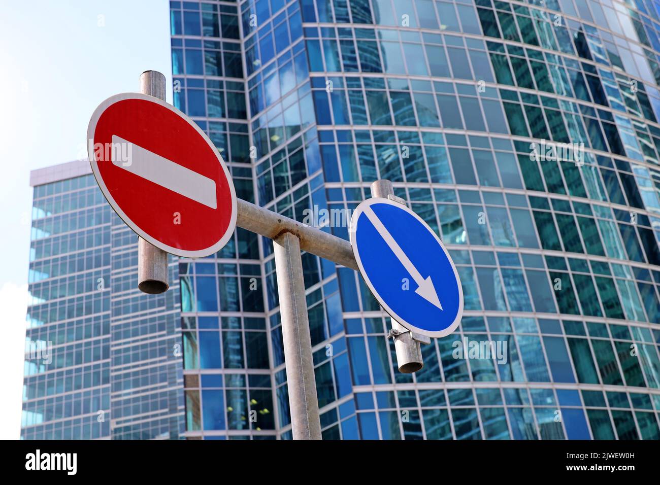 No entry sign and detour obstacles sign on the skyscraper background. Concept of economic sanctions, financial crisis Stock Photo