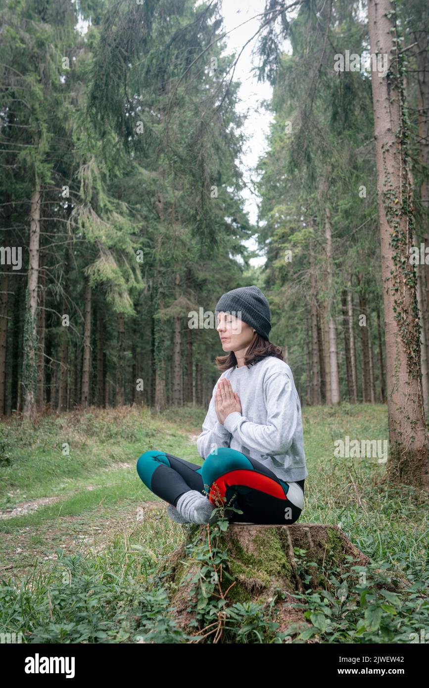 Yoga woman sitting and meditating in a forest. Stock Photo