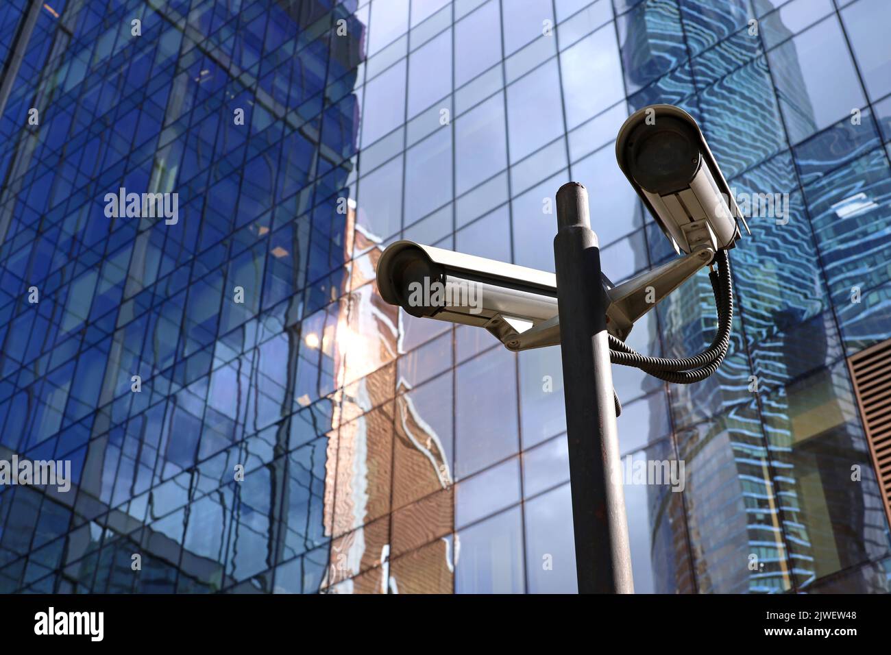 Outdoor surveillance video cameras on background of skyscraper tower. Cctv camera near business center, concept of security, privacy and protection Stock Photo