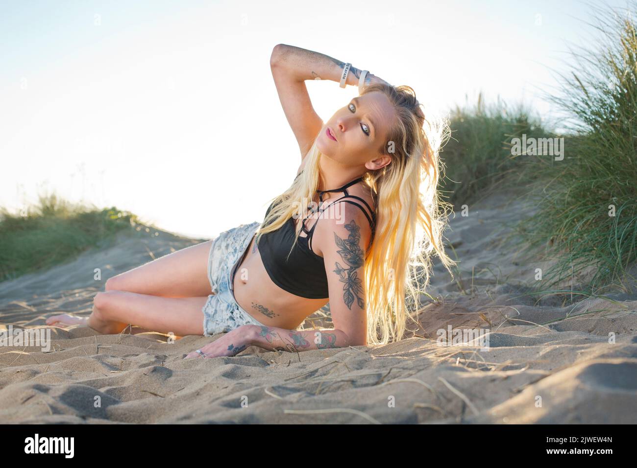Skinny tattooed model in sand dunes Stock Photo