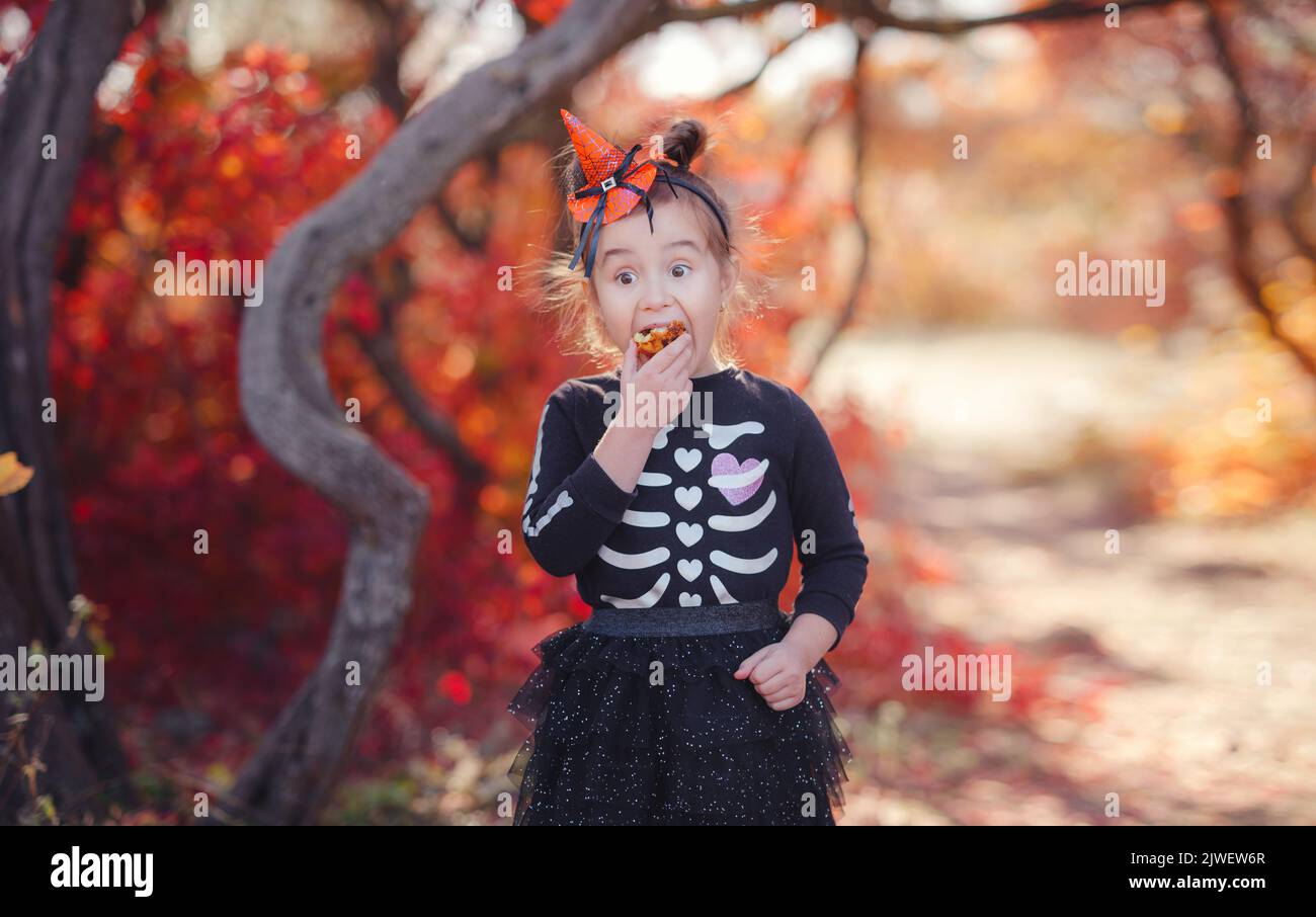 Young girl in black costume goes trick or treating. Little witch, Kids