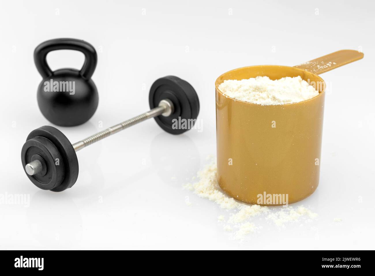 Scoop filled with protein powder, barbell and kettlebell isolated on white background, concept for intense resistance training technique, progressive Stock Photo