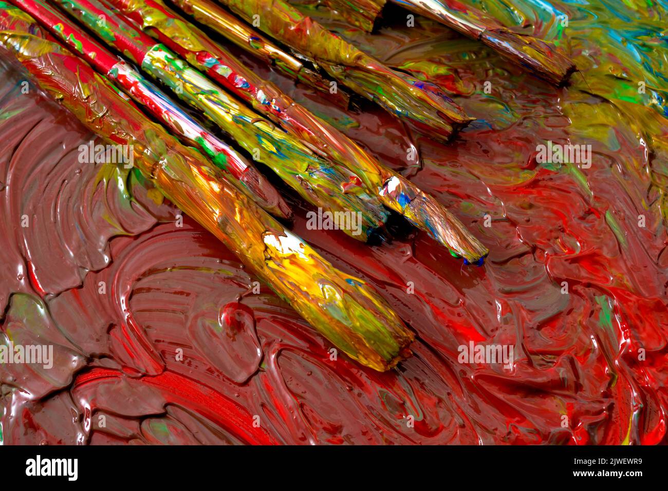 Close up on grungy paint brushes on messy artist canvas covered with oil paints conceptual representation for fine art gallery, visual artistic genius Stock Photo
