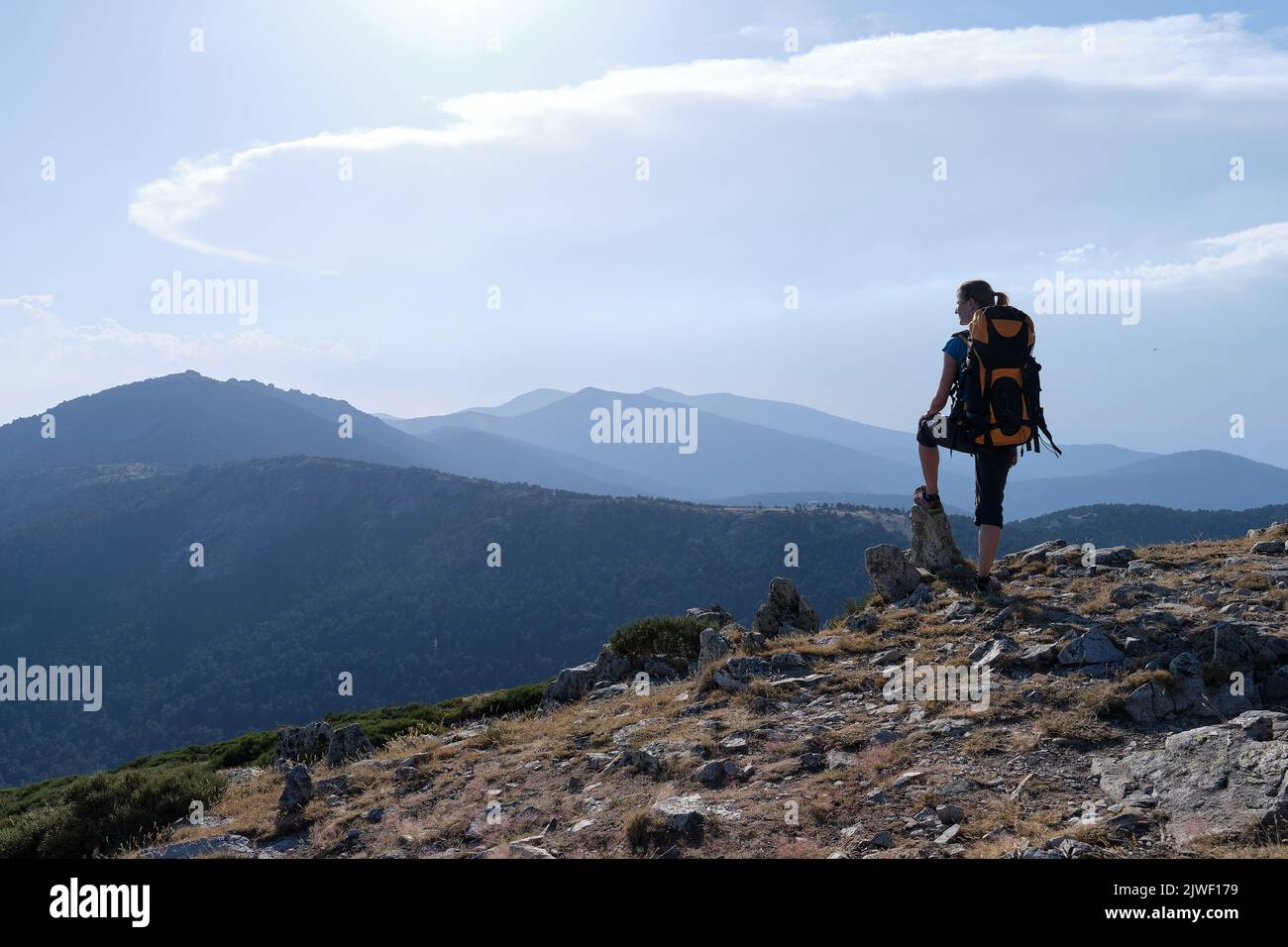 A Female traveler with backpack admiring mountains Stock Photo
