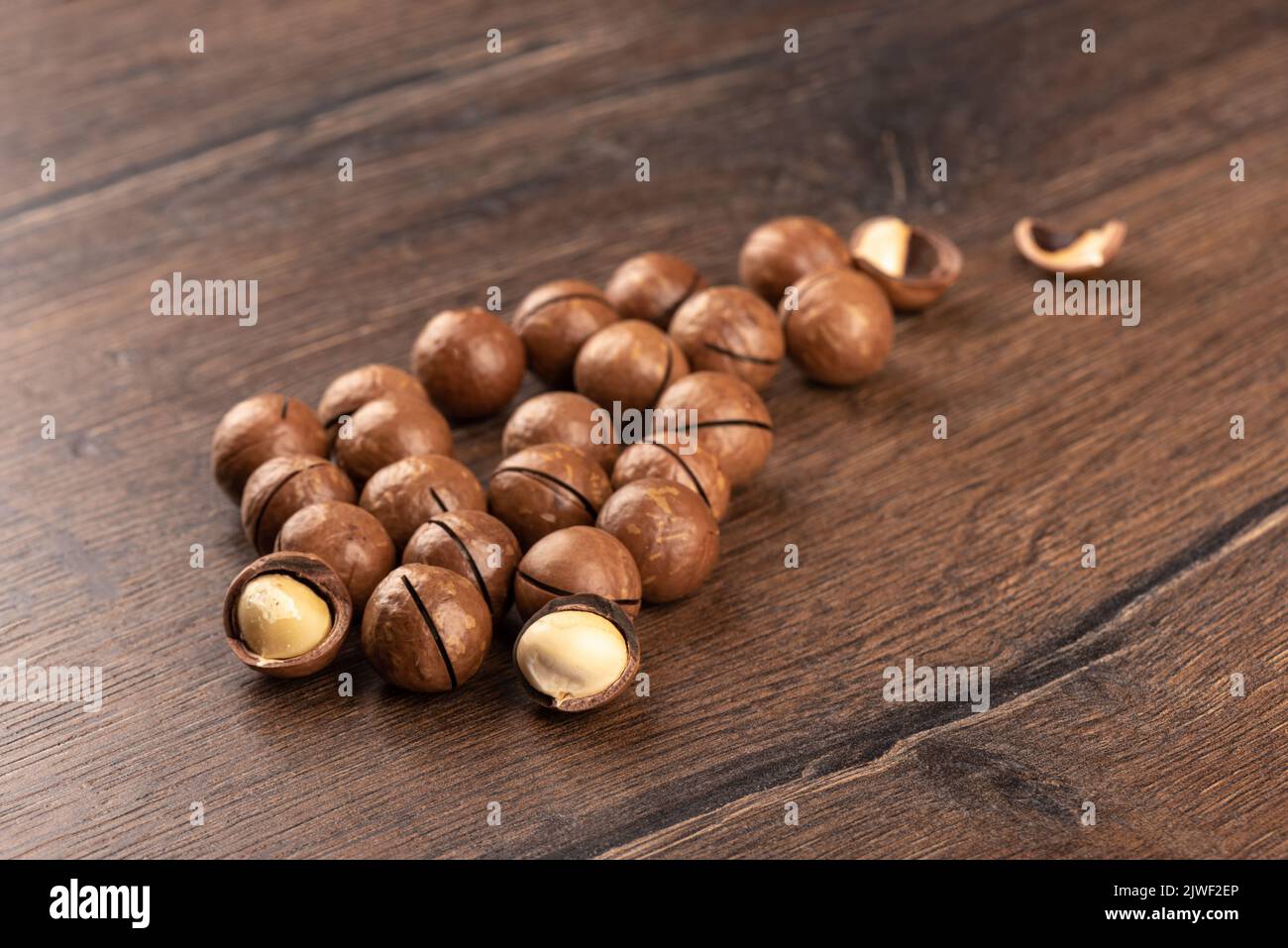 Selective focus on macadamia nuts over wooden background. Focus on the front of the nuts. The back of the nuts is blurred. Copy space. Stock Photo