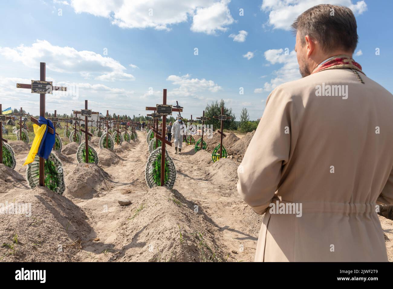 Bucha, Ukraine. 2nd Sep, 2022. A priest is seen reading a prayer for the repose of the souls of the innocent victims of Russian aggression. Burial of the remains of 13 unidentified and two identified people who were killed in the Buchan district during the Russian occupation, on September 2, 2022. A few months after the de-occupation of the Bucha district, those bodies that were not identified were buried and marked with numbers at the cemetery in Bucha. According to the deputy mayor of Buch Mykhailyna Skoryk, a total of 419 people who were killed during the Russian occupation of the Bucha Stock Photo