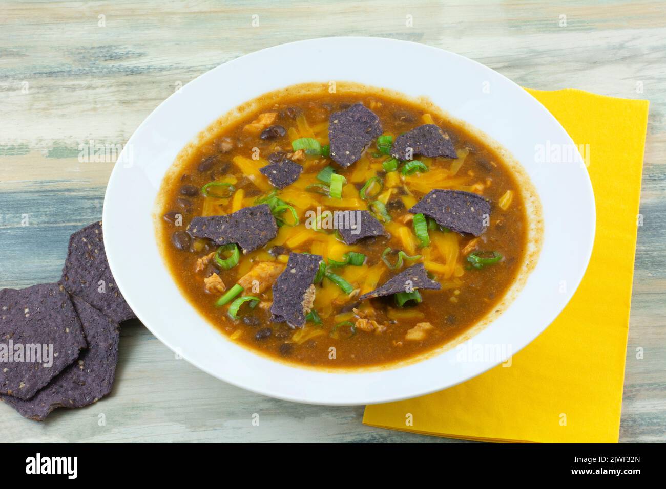 Chicken and black bean soup with blue corn tortilla chips in white bowl