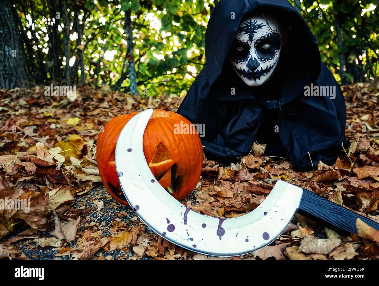 Young woman with halloween paint face mask wearing black hood Stock