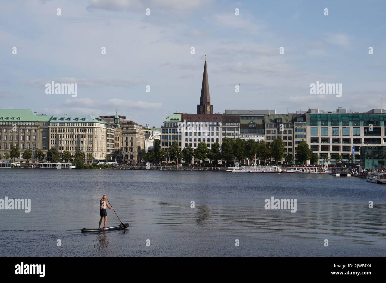Man standing on a stand up paddle board is paddling on Binnenalster in Hamburg. Stock Photo