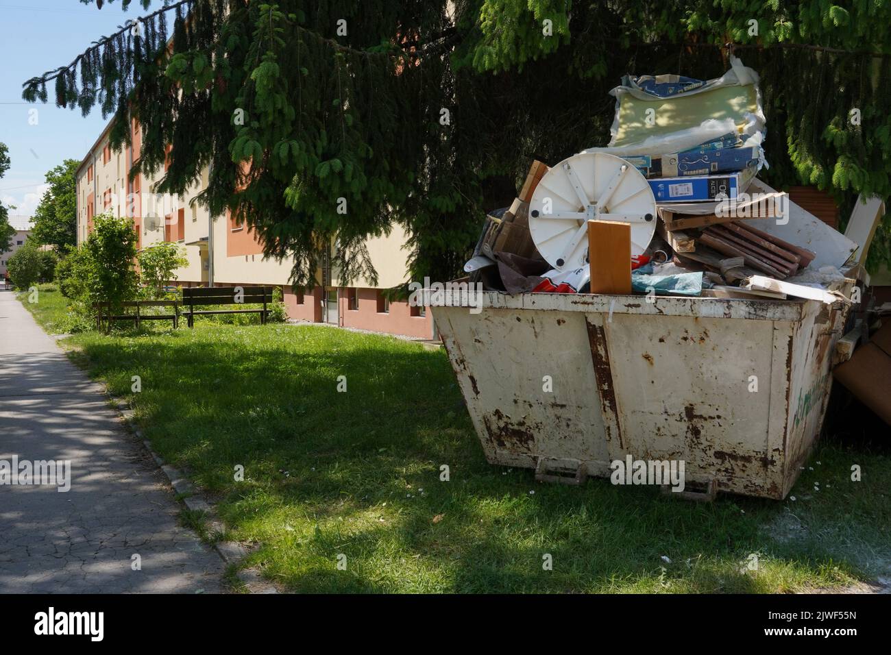Large waste container filled with bulky waste, old furniture and other
