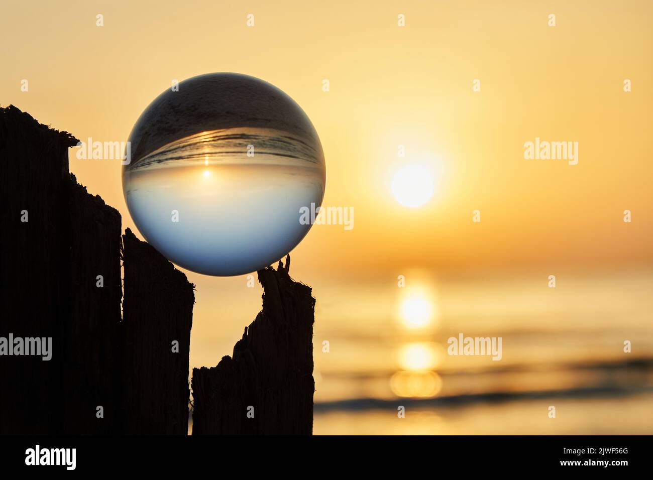 View on a sunset over ocean coast through a glass ball. Selective focus. Stock Photo