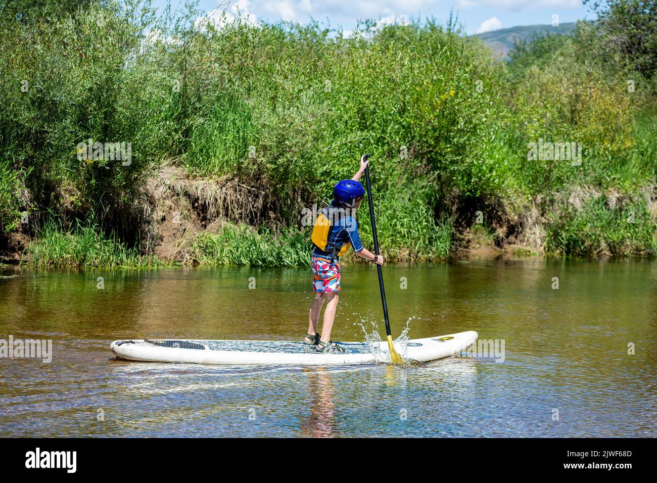 Stand up paddle boarding boy, Roaring Fork River, near Aspen, Colorado USA Stock Photo