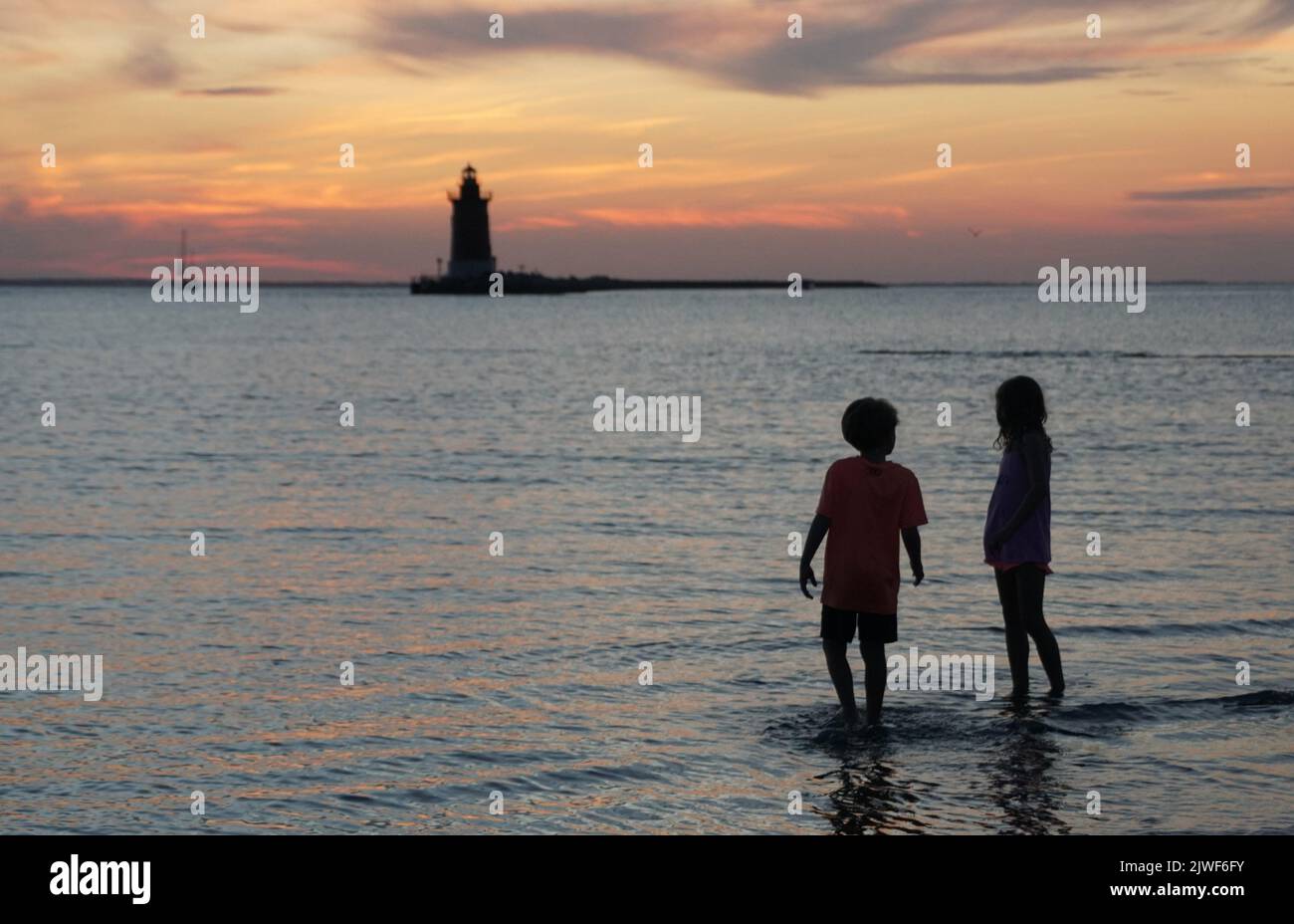 Silhouette of young kids enjoying the sunset at Cape Henlopen State Park, Lewes, Delaware, U.S.A Stock Photo