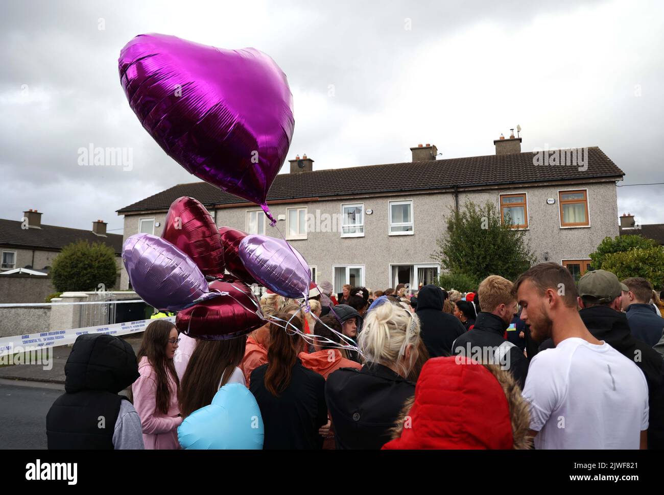 People attend a vigil outside a house on Rossfield Avenue in Tallaght