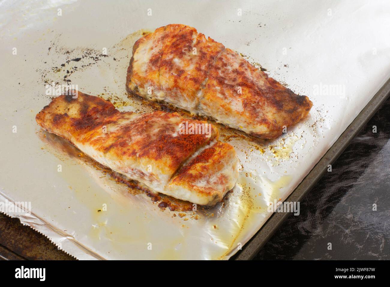 Two baked barramundi fish fillet slices with paprika spice rub on