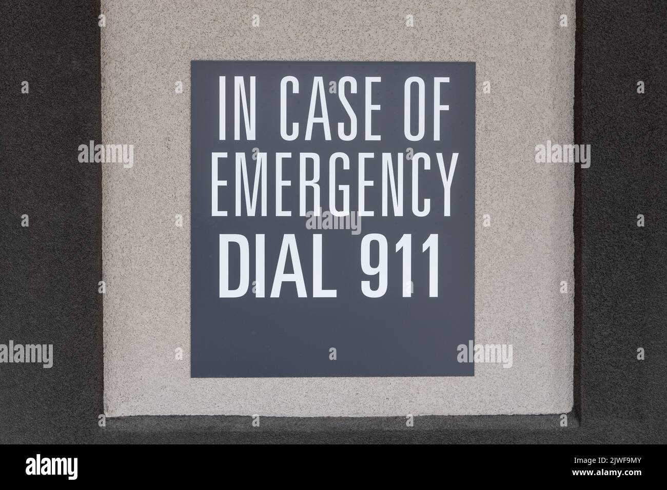 Gray sign on the wall depicting the emergency number, sign with inscription: in case of emergency dial 911 Stock Photo