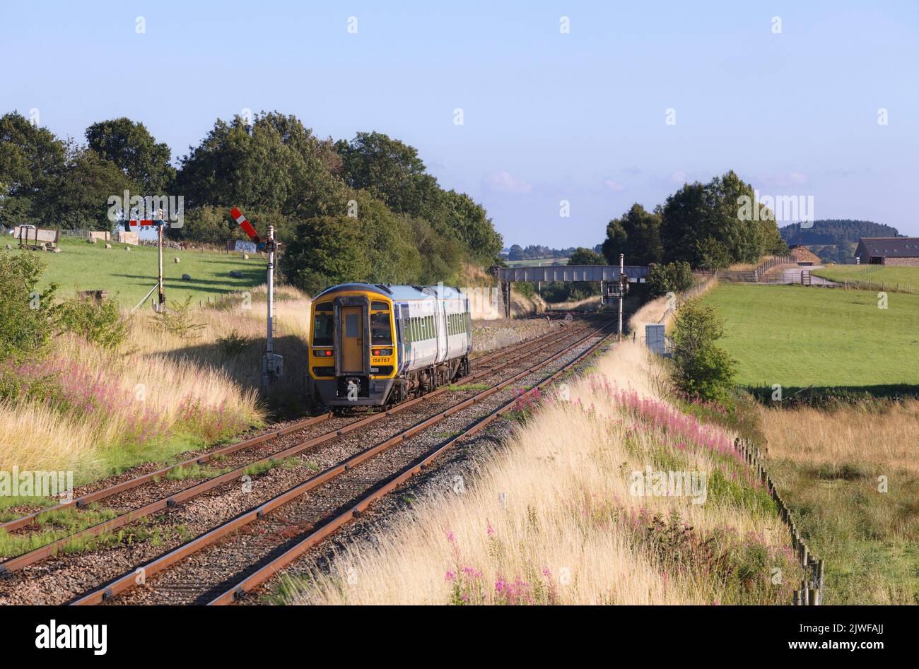 Northern rail class 158 Diesel multiple unit  train passing the mechanical semaphore signals at Settle junction, Yorkshire, UK Stock Photo