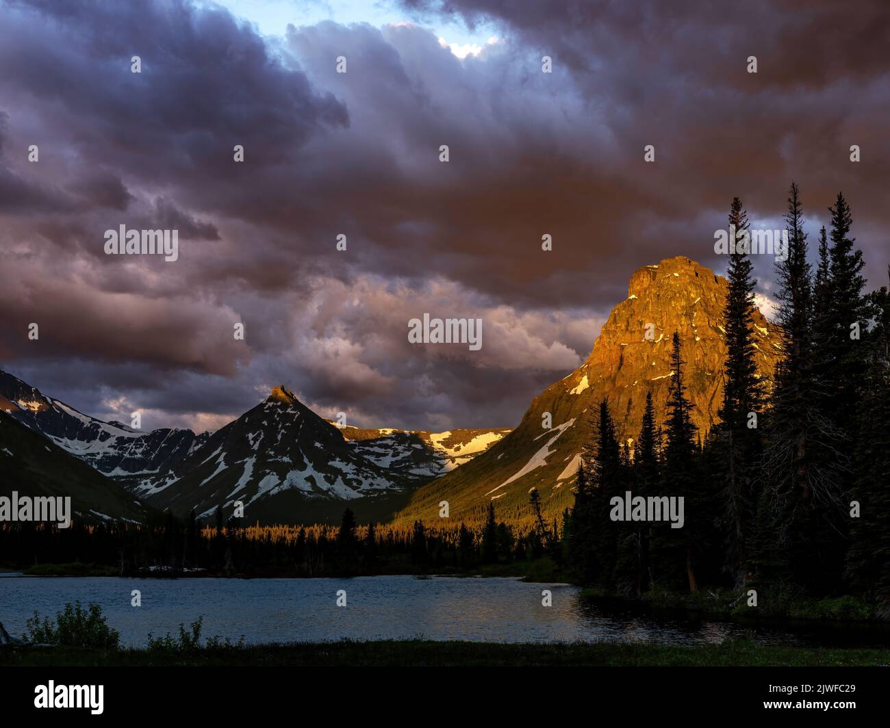 Dramatic cloud sunrise in Glacier National Park with Lake and Mountains Stock Photo