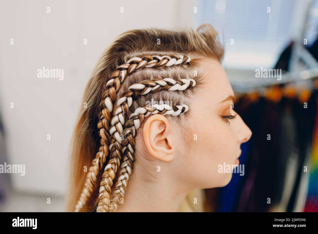 Hairstylist braided afro braids dreadlocks kanekalon pigtails hair of female client in barber salon. Stock Photo
