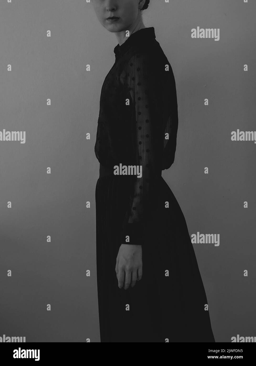 A beautiful Caucasian girl in black Victorian-style dress standing