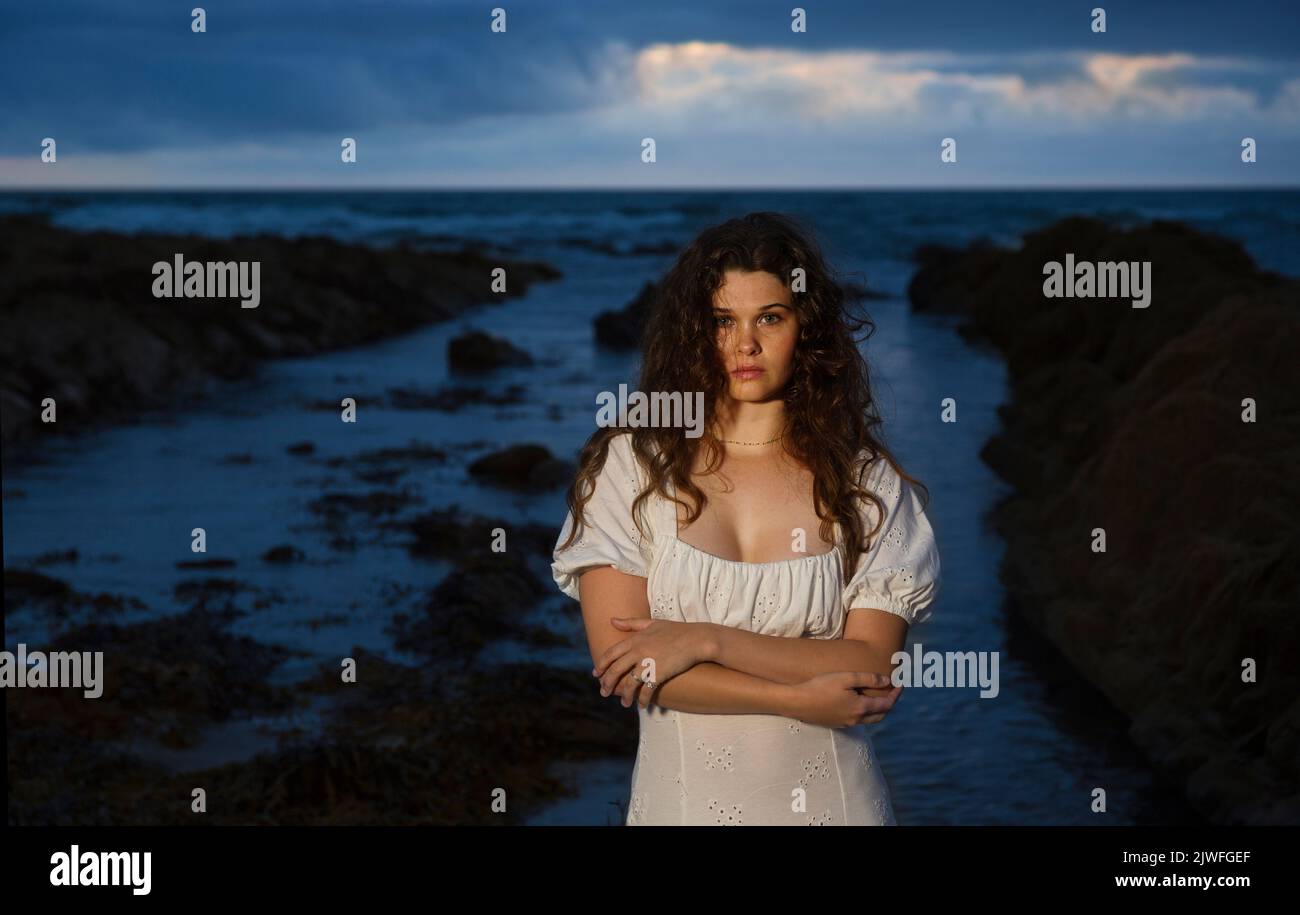 A beautiful woman with wild hair on Widemouth beach on a stormy night. Stock Photo
