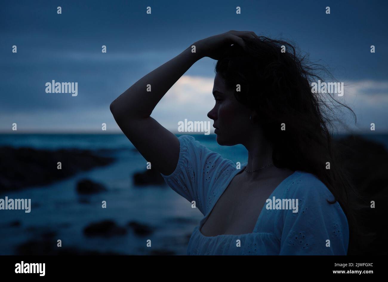 A beautiful woman with wild hair on Widemouth beach on a stormy night. Stock Photo