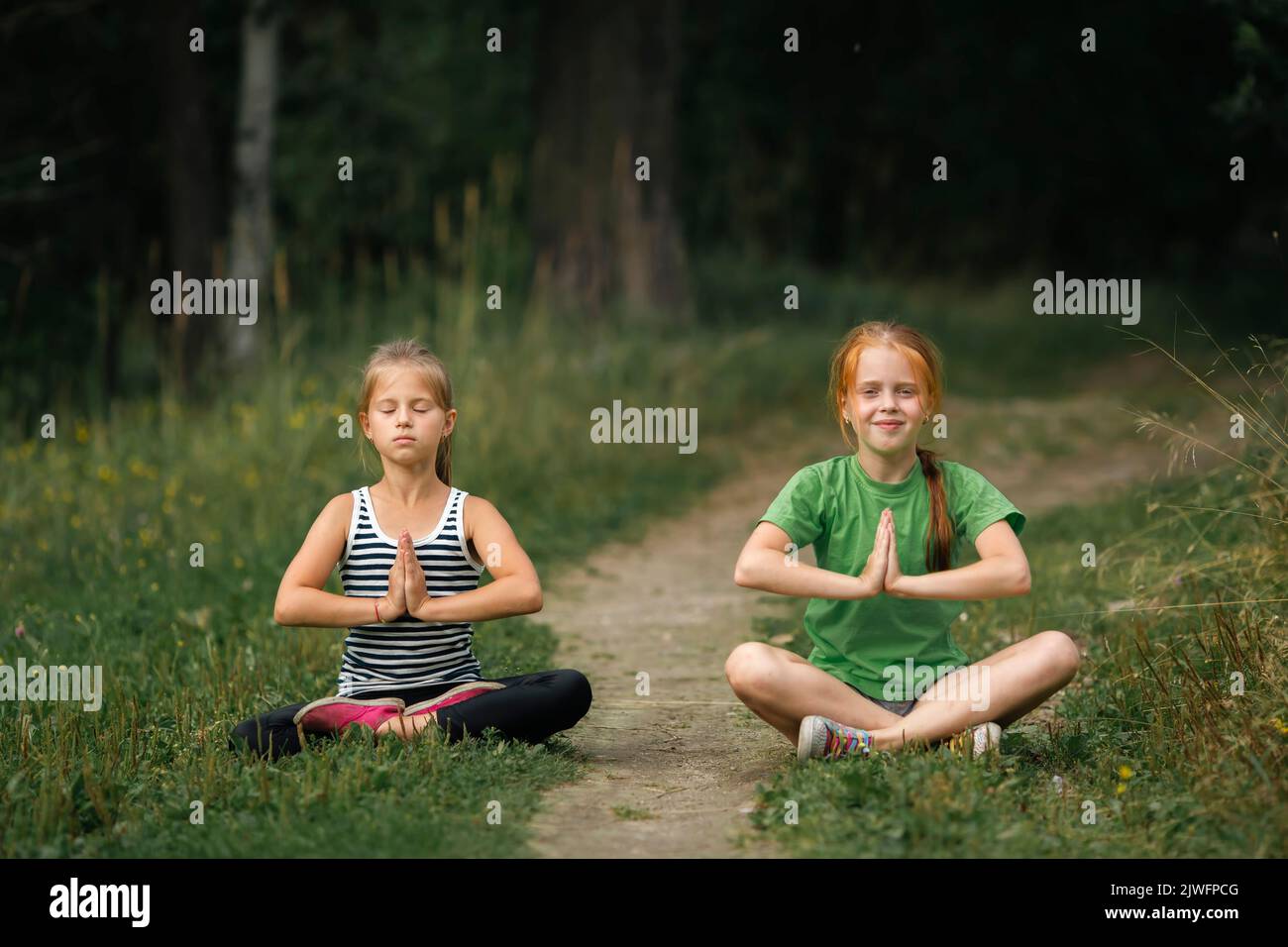Two girls girlfriends meditate in the park. Stock Photo