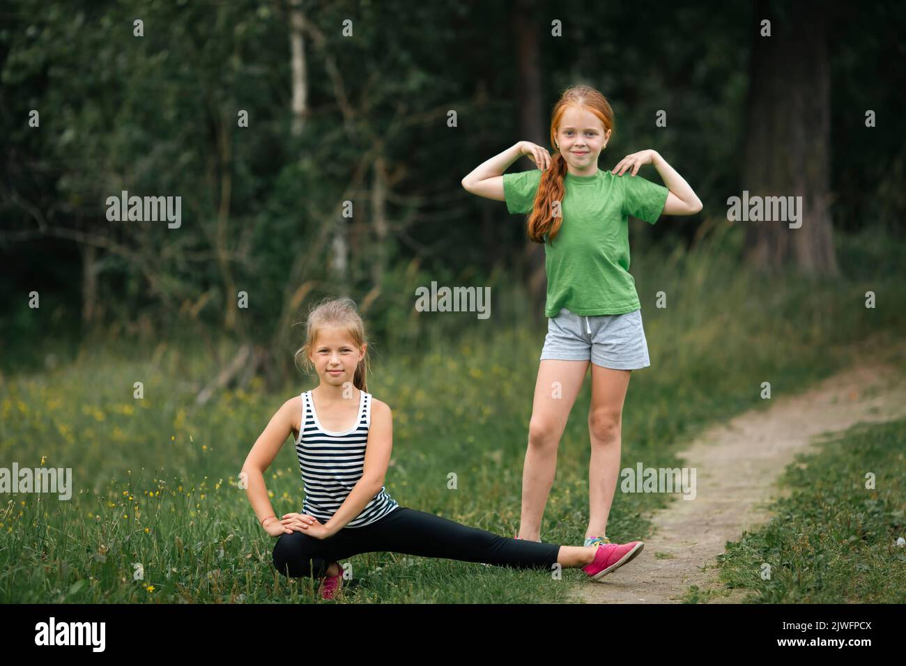 Two teen girls warming up before a jog in the park. Stock Photo
