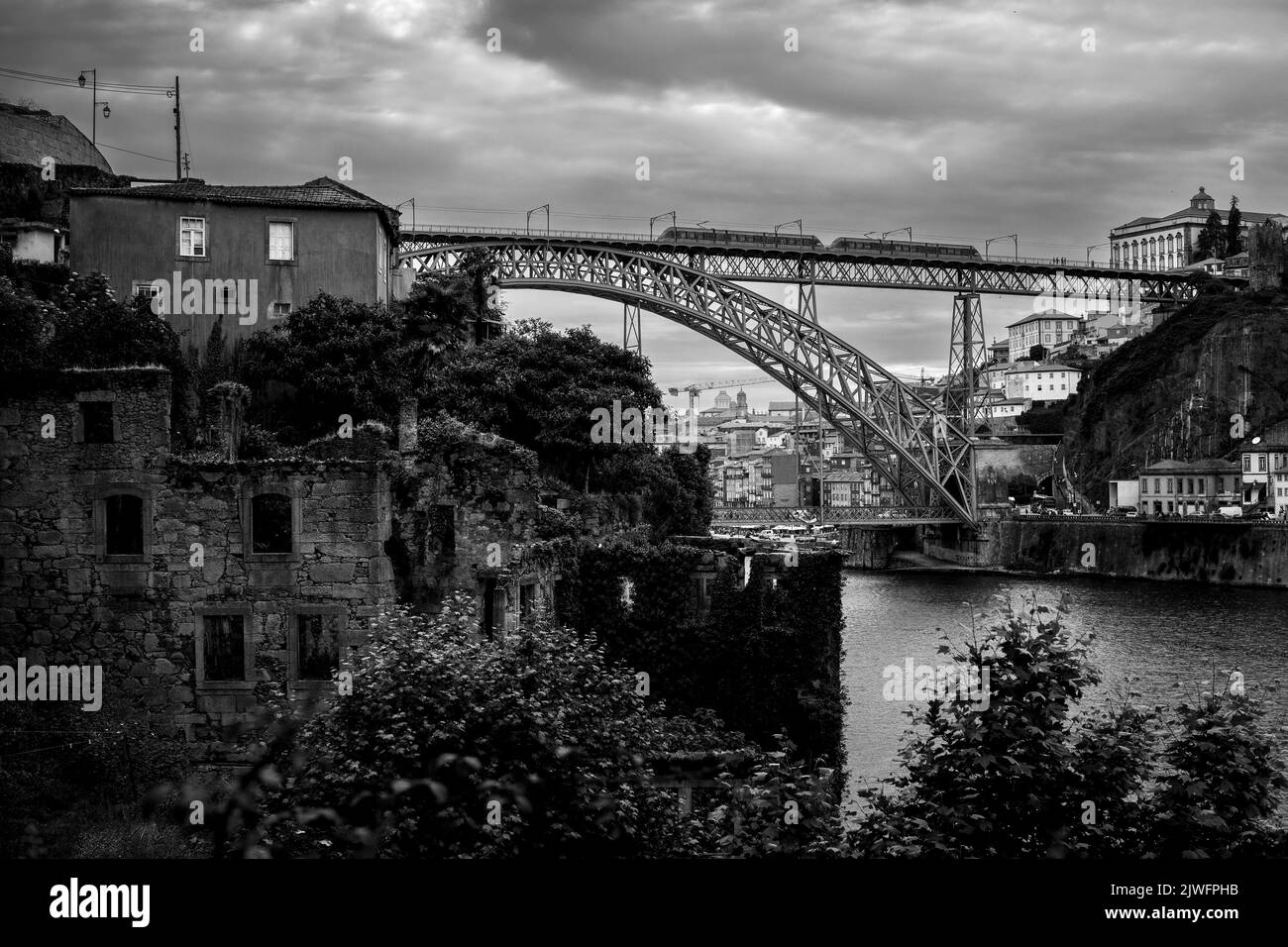 Abandoned buildings on the banks of the Douro with Dom Luis I Bridge in the background, Porto, Portugal. Black and  white photo. Stock Photo
