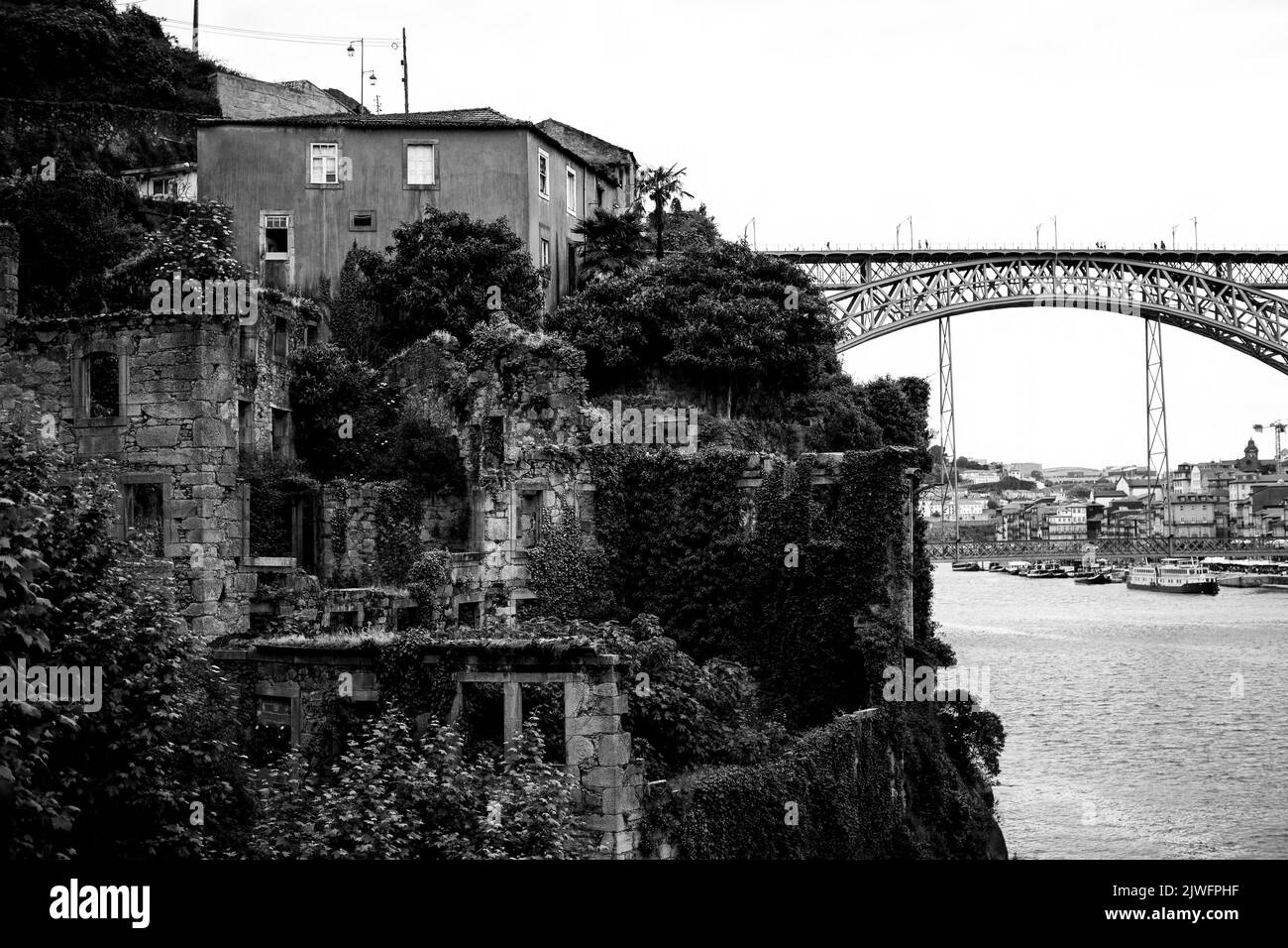 Abandoned ruins of a building on the banks of the Douro with Dom Luis I Bridge in the background in Porto, Portugal. Black and  white photo. Stock Photo