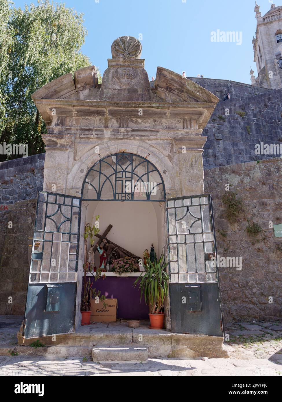 Stone built religious shrine with glass and metal doors and a with a crucifix inside, in front of the walls of the Cathedral, Porto, Portugal Stock Photo