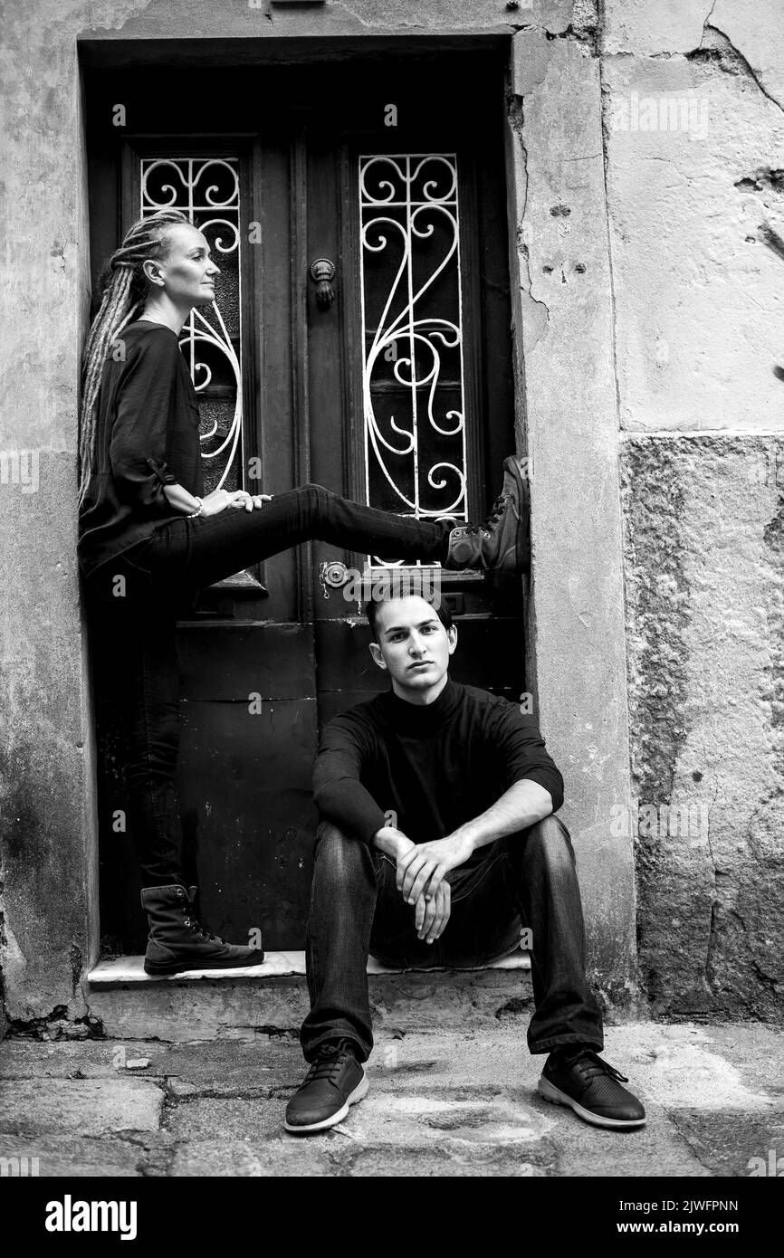 A woman and young man posing near the door on the street of an old European city. Black and white photo. Stock Photo