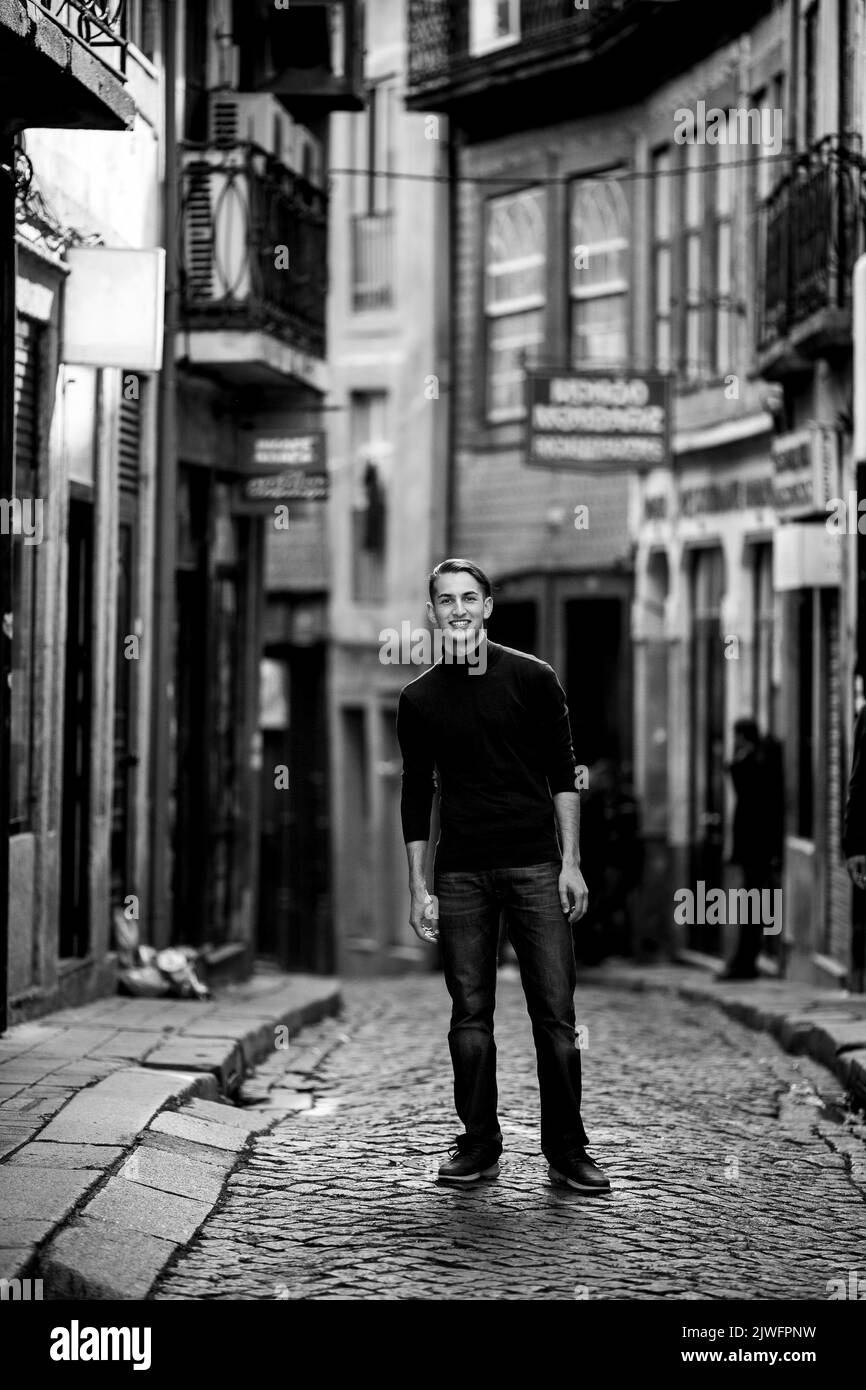 A handsome young man on the streets of an old European city. Black and white photo. Stock Photo