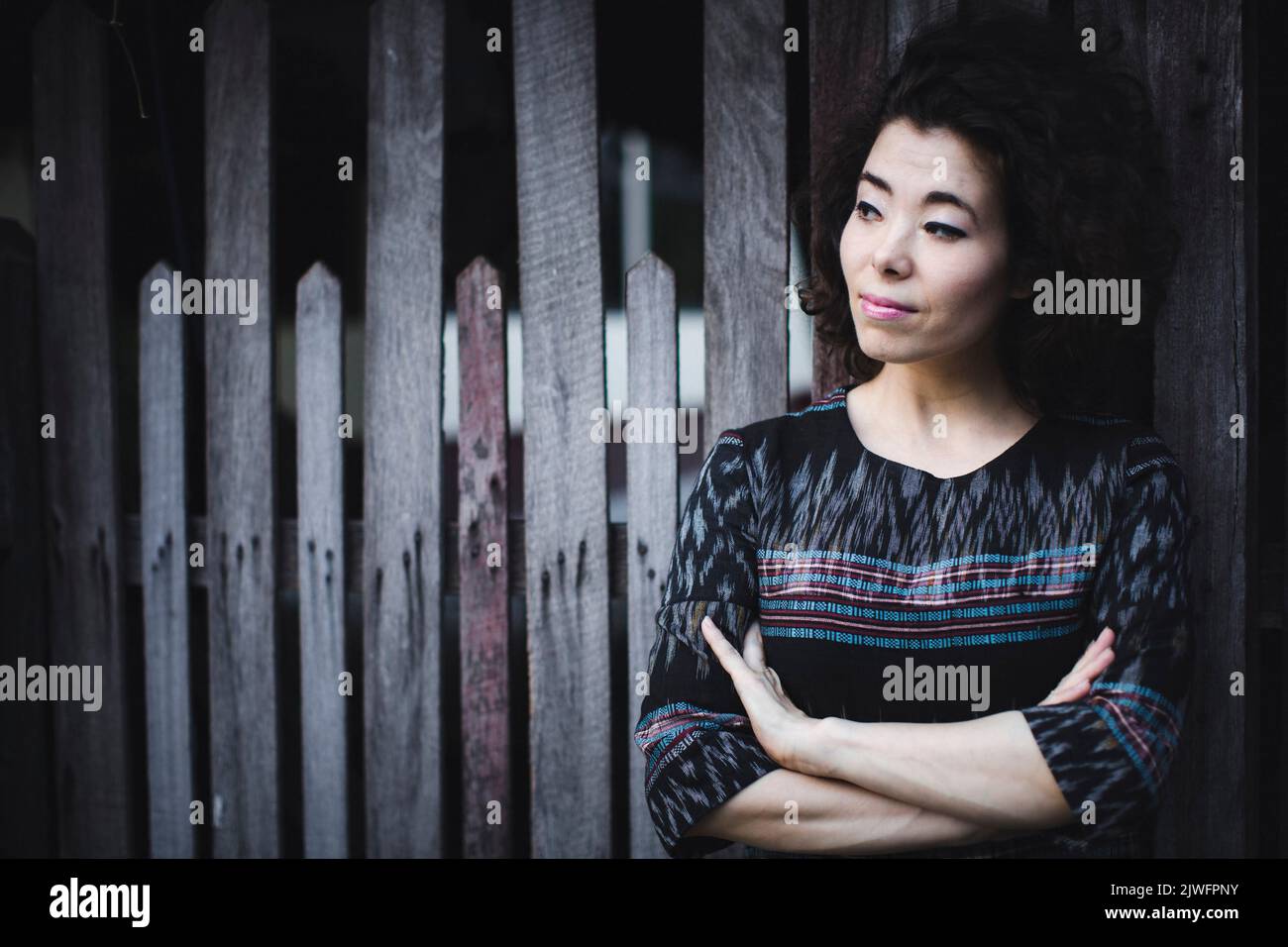 Portrait of an Asian woman near a wooden fence. Stock Photo