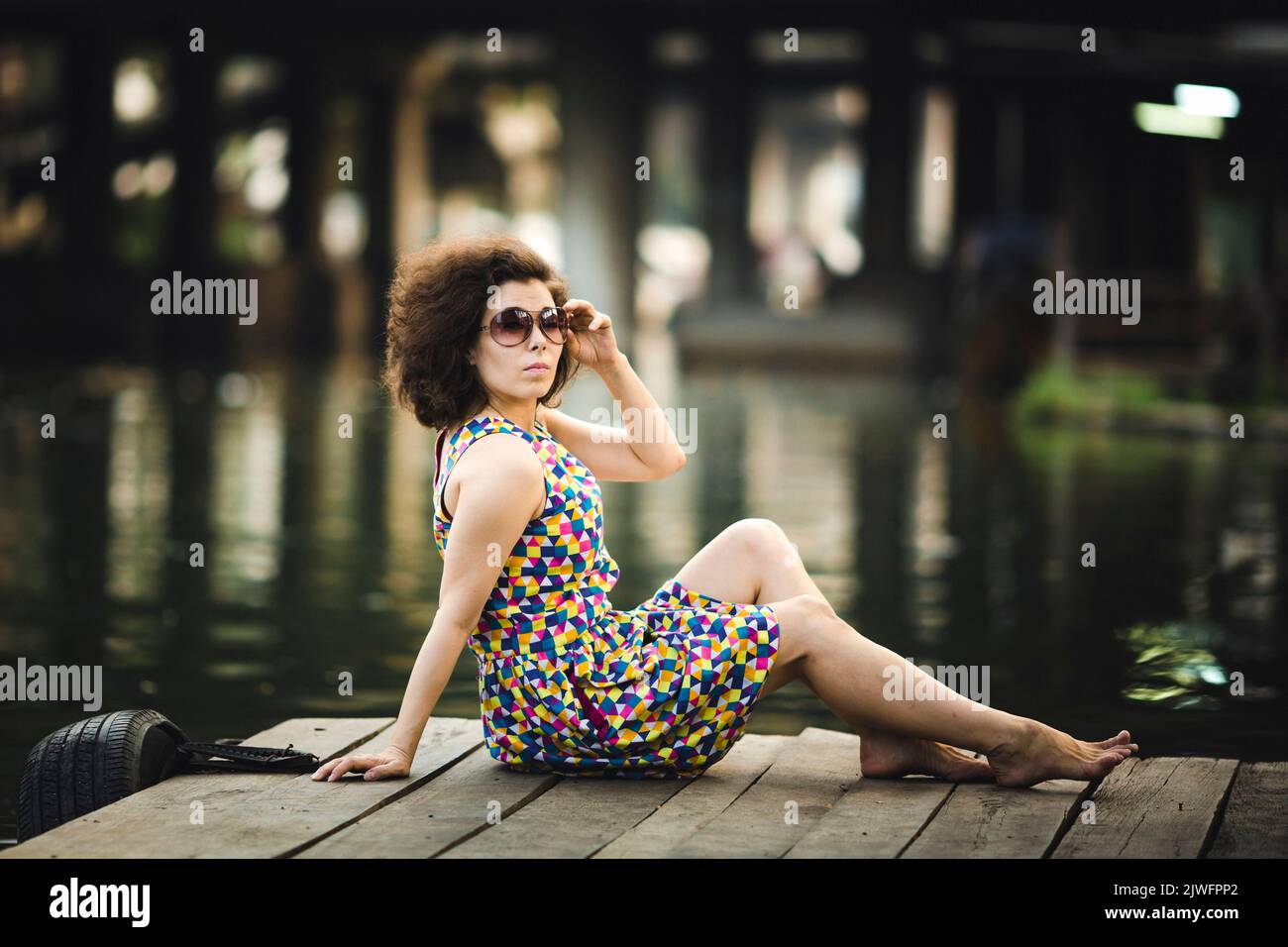 A portrait of an Asian woman sitting on a riverfront. Stock Photo