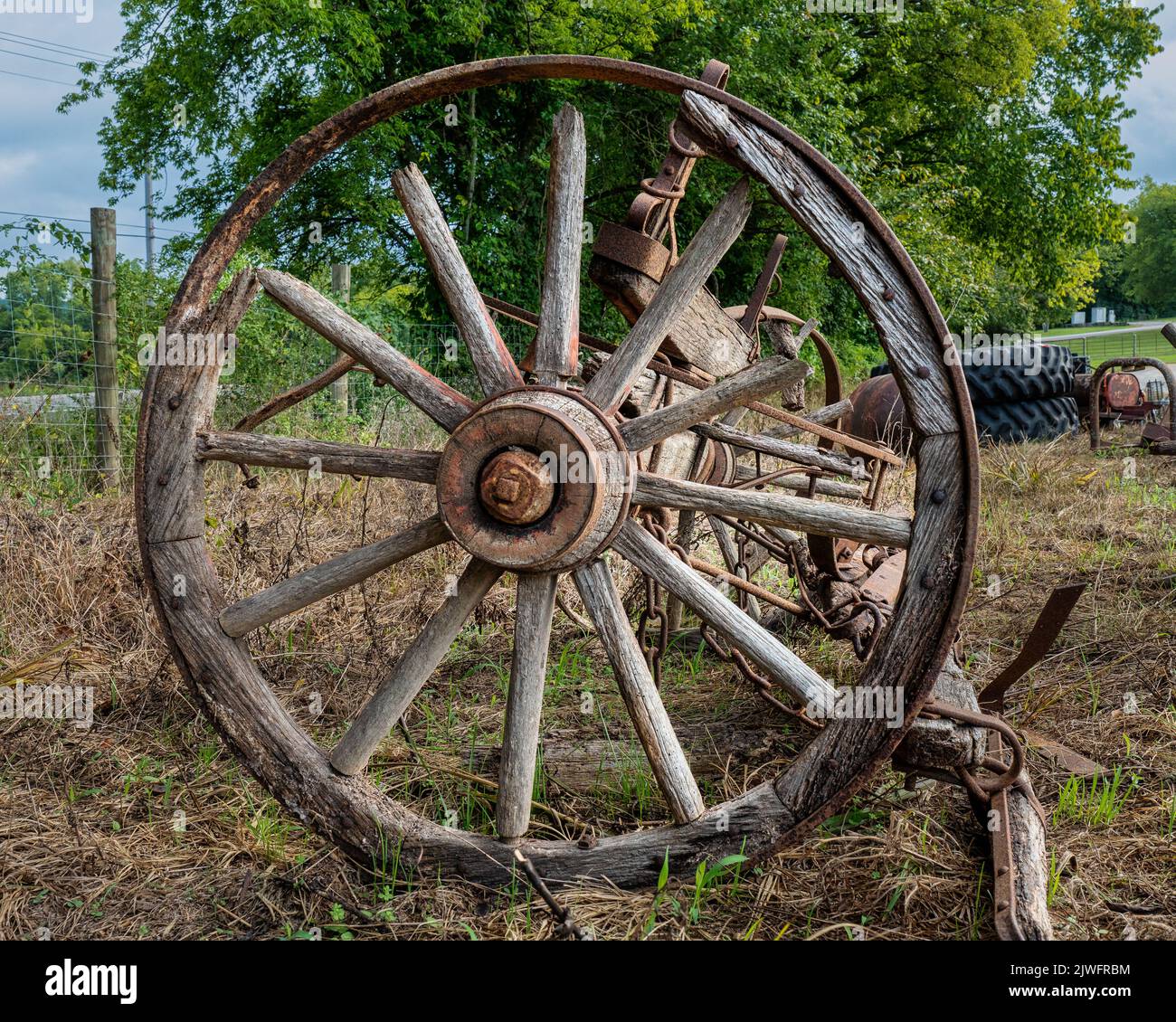 Weathered old cracked and rusted wooden spoked wagon wheel. Stock Photo