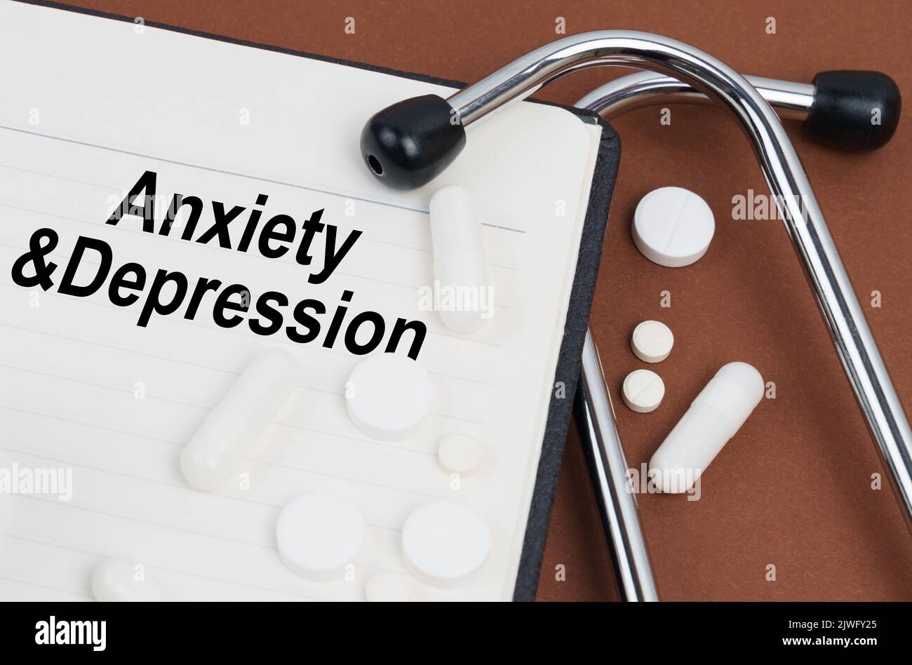 Medical concept. On a brown surface lies a stethoscope, pills and a notepad with the inscription - Anxiety and Depression Stock Photo