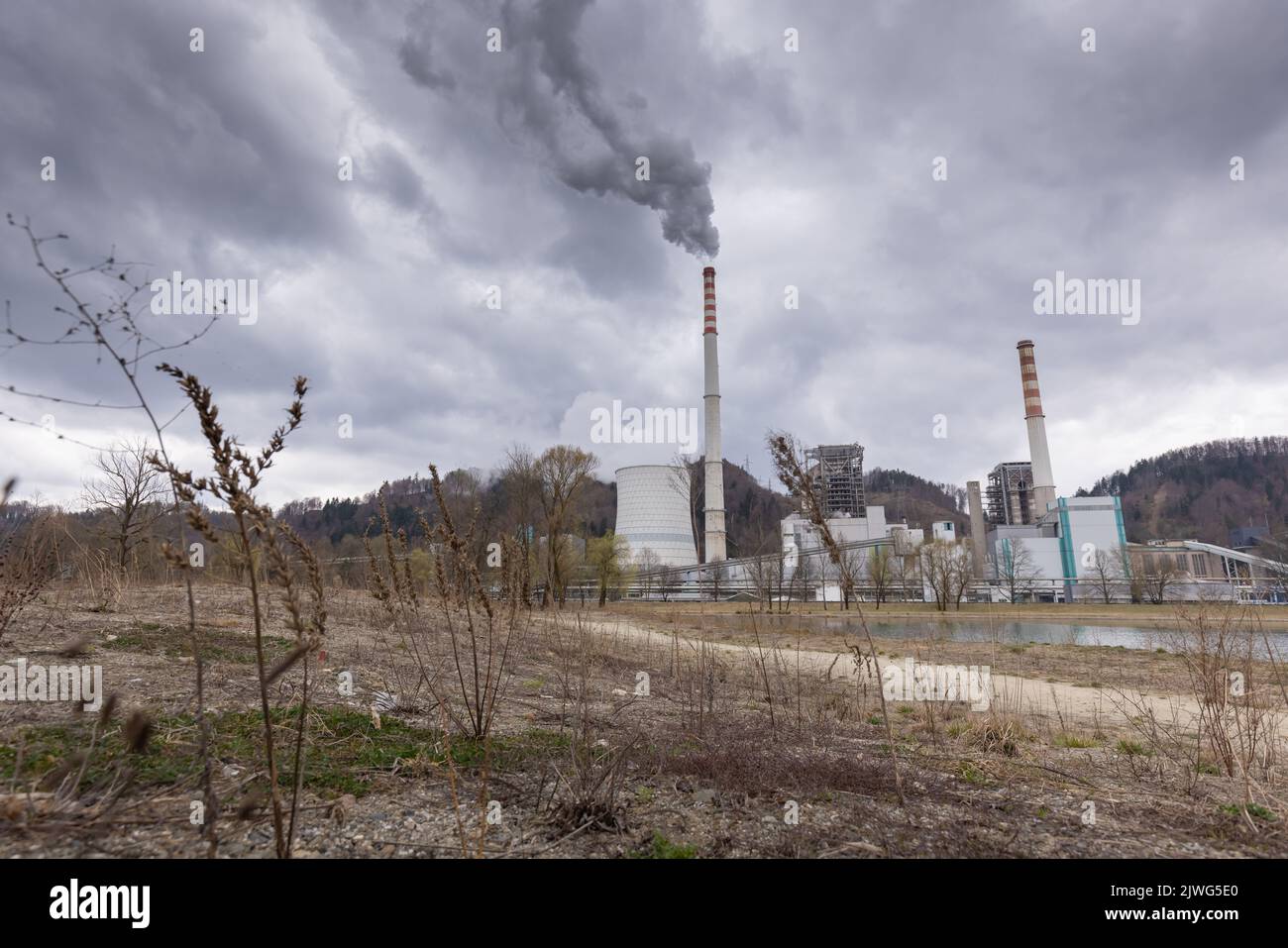 Thermal power plant burning coal with large cooling tower, emitting