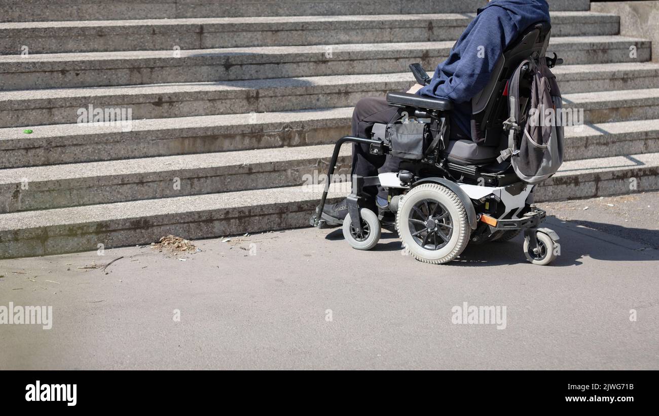 Man with disability on wheelchair stopped in front of staircase