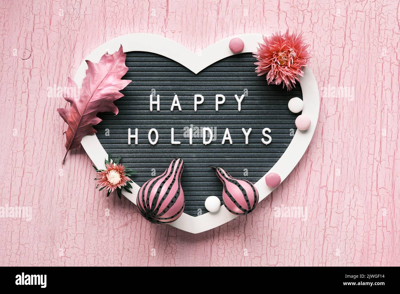 Heart shaped letter board with pink Fall decor. Text Happy Holidays on