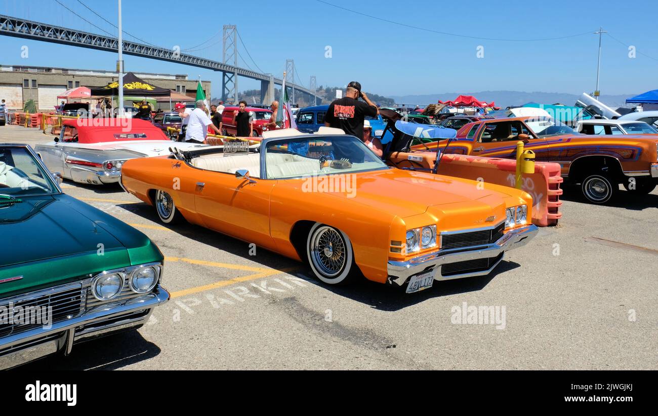 Orange colored convertible Chevy Impala lowrider at a car show in San