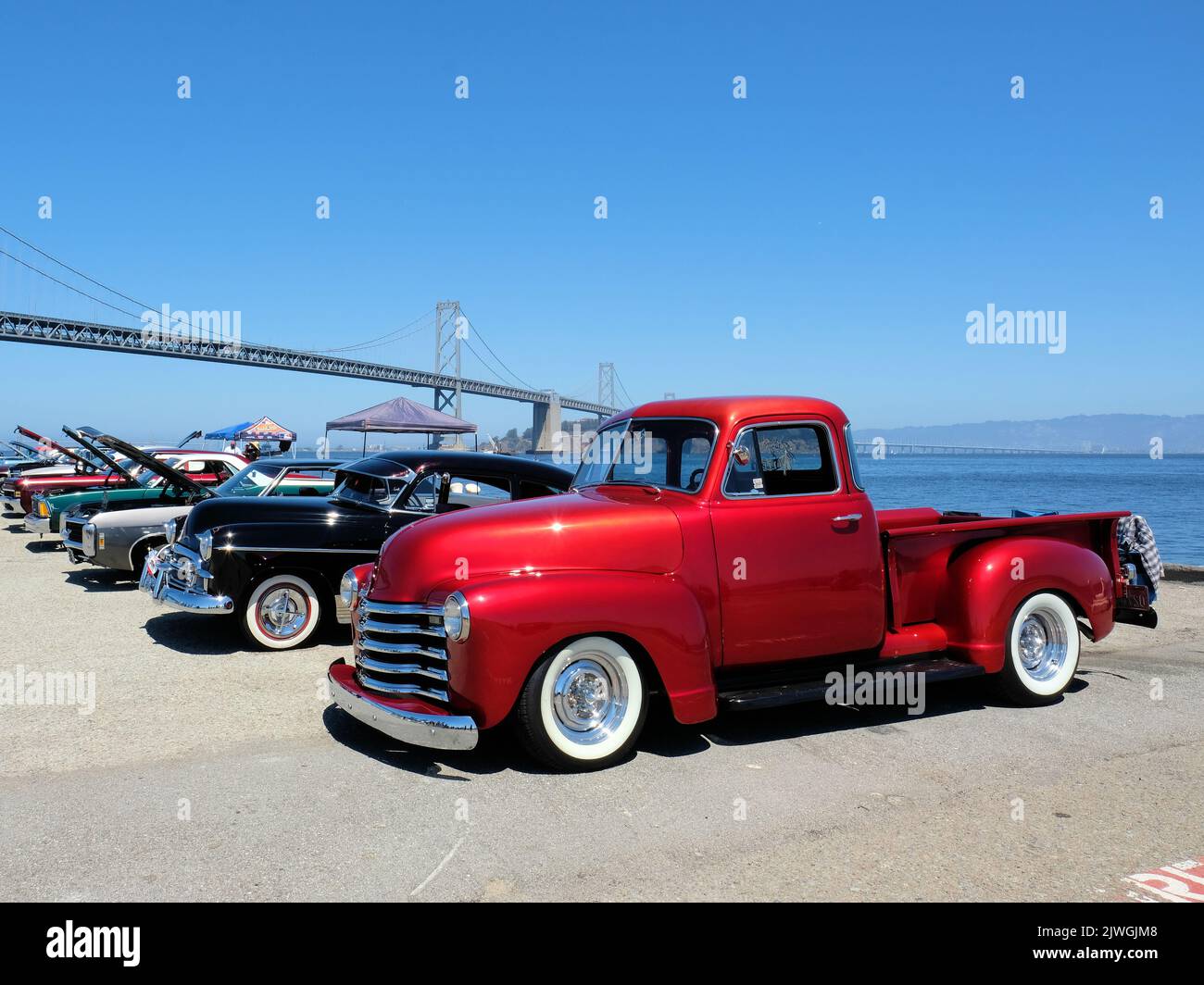 Candy apple red 1950 Chevy Thriftmaster pickup at a car show along the