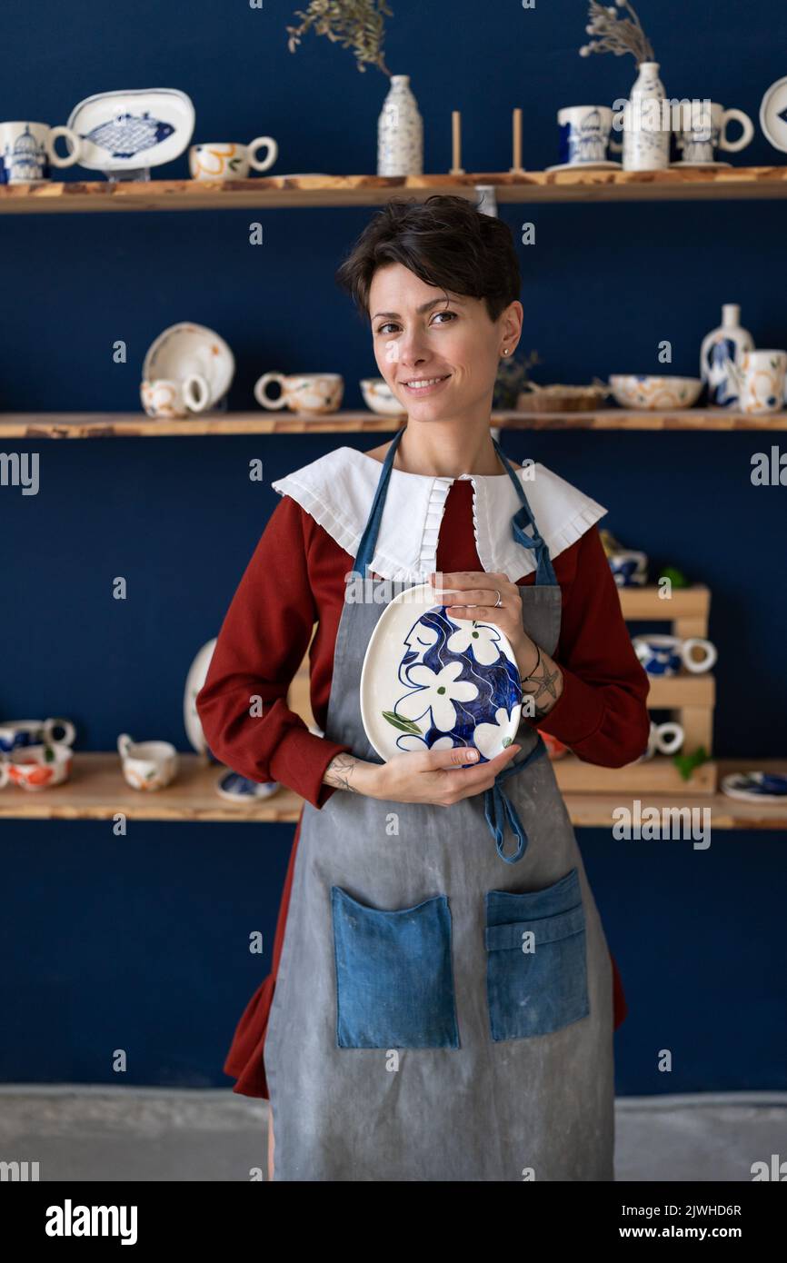 Successful ceramics studio owner posing with handmade plate at