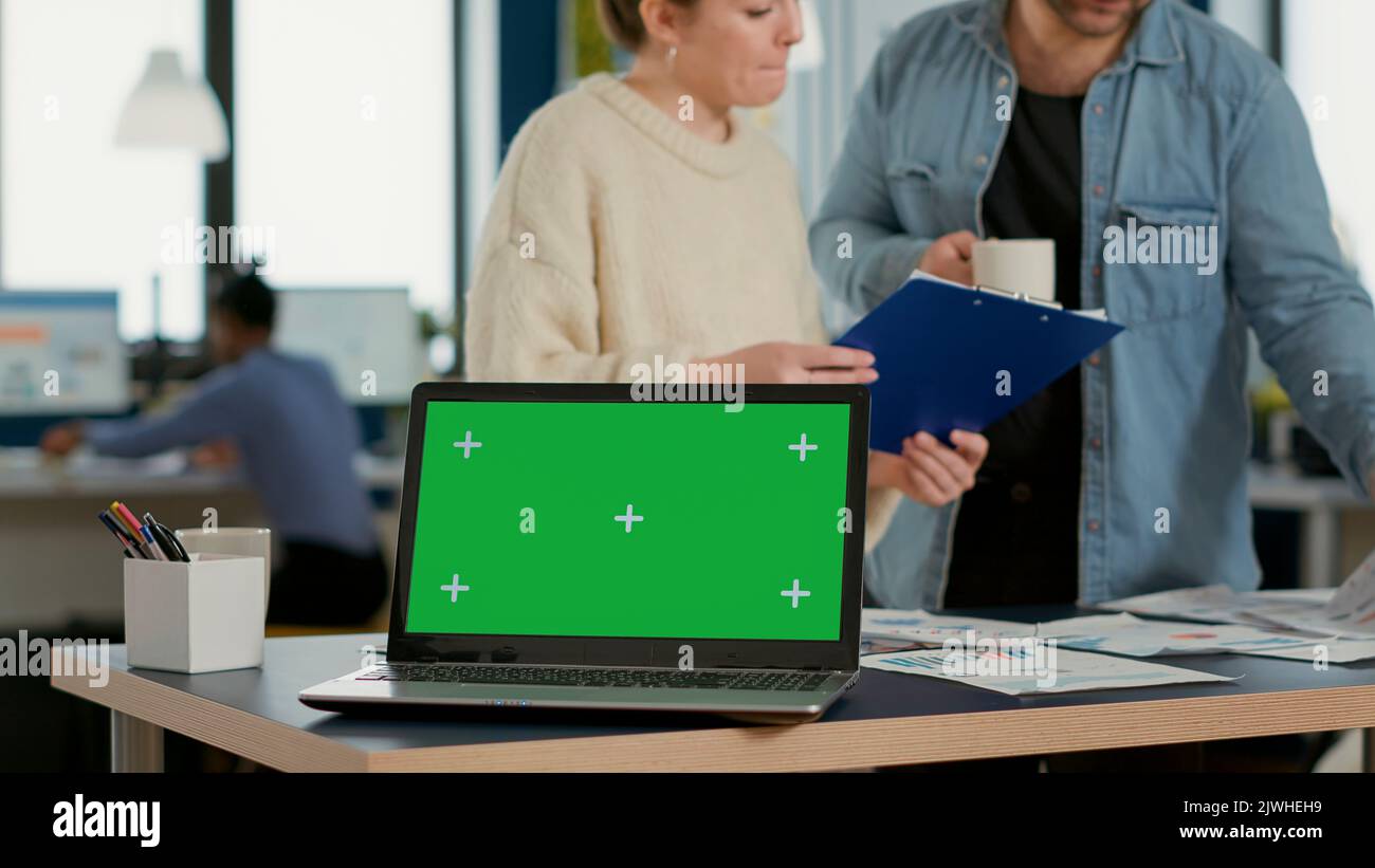 Laptop computer with green screen on desk in front of startup